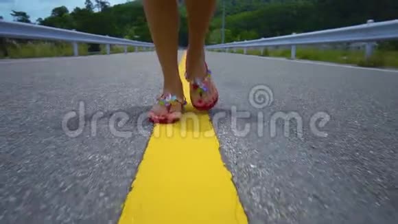 一个女孩的腿沿着一条黄色的分割条沿着马路走视频的预览图