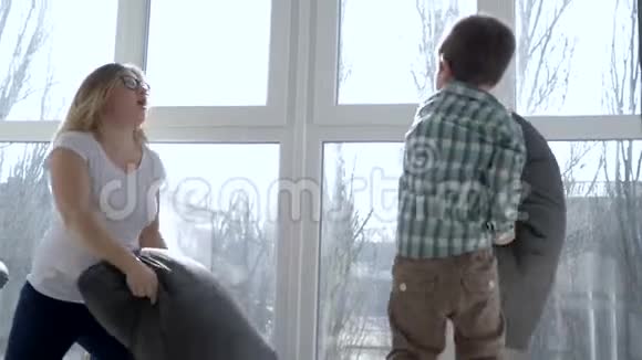 家庭娱乐妈妈和儿子把枕头扔在家靠窗的地方视频的预览图