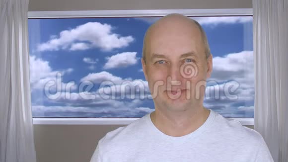 成熟的男人微笑着站在房间里窗外有蓝色的多云天空视频的预览图