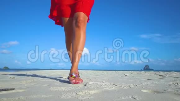 女孩穿着红色连衣裙沿着白色沙滩散步的腿视频的预览图