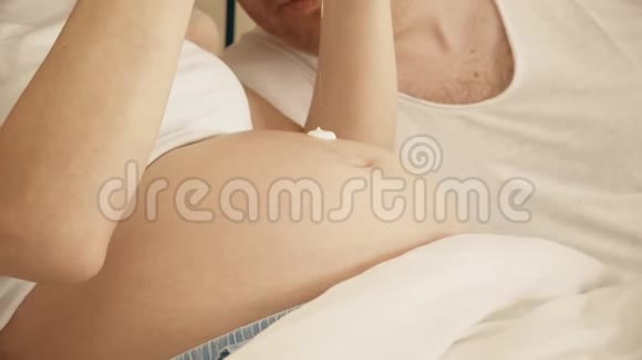 未知孕妇腹部涂奶油特写镜头视频的预览图