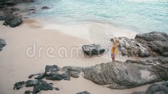 在美丽的热带白沙滩上年轻女子穿着黄色泳衣走开视频的预览图