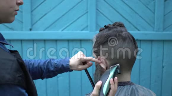 女性理发师在露天理发厅用电动剃须刀和梳子理发视频的预览图