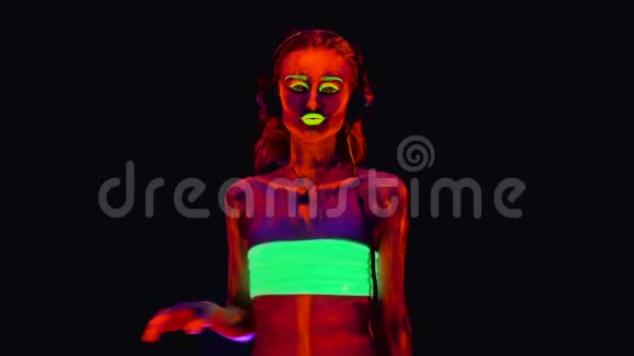 一个戴着耳机半裸着身子的年轻美女带着紫外线在她的身体上跳舞很漂亮视频的预览图