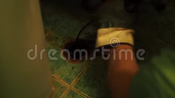 戴橡胶手套的人把金属电缆推到地板上的一个洞里视频的预览图