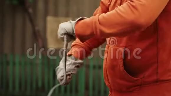戴工作手套的人顺时针旋转一根金属电缆前景视频的预览图