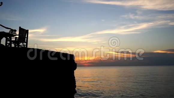 在美丽的夕阳下勇敢的女孩用GoPro动作相机从岩石上跳进海里慢动作1920x1080视频的预览图