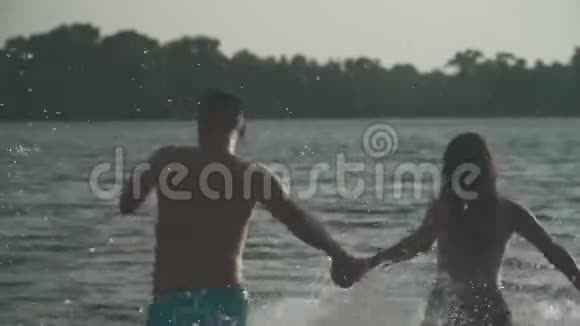 英俊的男人和漂亮的女孩牵着手跑进河里视频的预览图