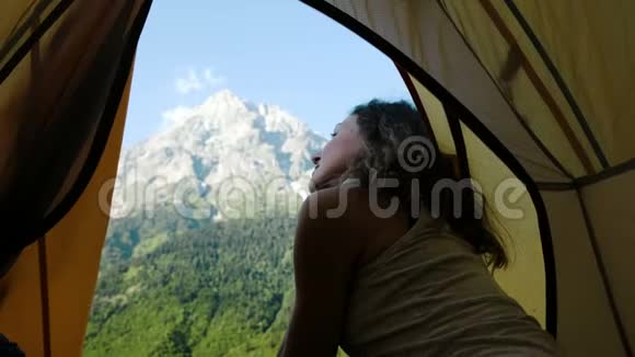 快乐的旅游女孩从背景上的帐篷里望出去看着那座高山视频的预览图