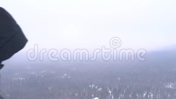 一个背着背包的年轻人爬上了白雪覆盖的山顶视频的预览图