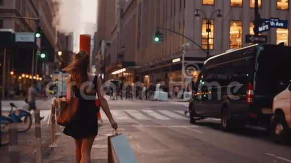 年轻漂亮的女人带着购物袋走路穿过美国纽约市中心的交通道路视频的预览图