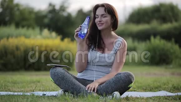 健身美女在公园锻炼后喝水的莲花姿势视频的预览图