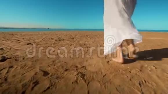 穿着白色长裙的白种人女孩在沙滩上赤脚行走的腿视频的预览图