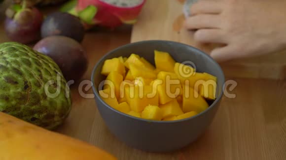 慢镜头一位年轻女子将火龙果放入灰色陶瓷碗和许多热带水果视频的预览图