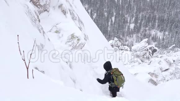 一个年轻人一个游客肩膀上有一个背包上升到一座白雪覆盖的山顶视频的预览图
