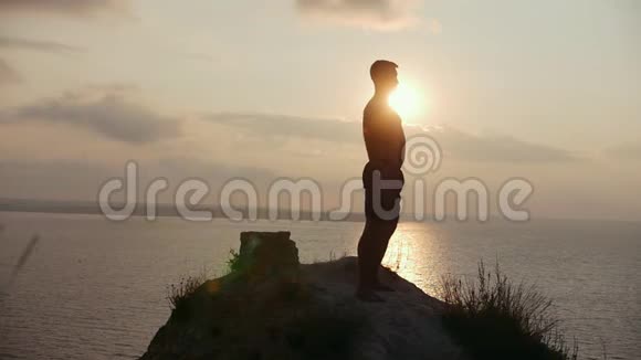 日出时年轻人在悬崖上蹲着视频的预览图