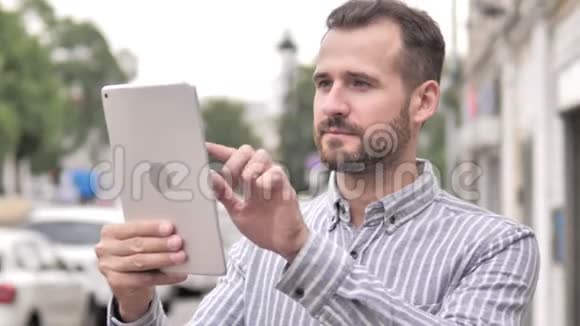 胡子休闲男子使用平板电脑户外视频的预览图