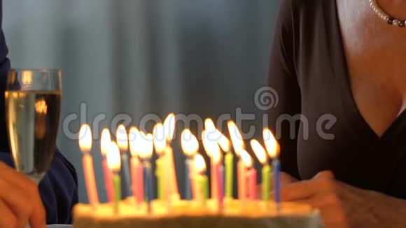老太太在蛋糕上吹蜡烛和丈夫一起庆祝生日视频的预览图