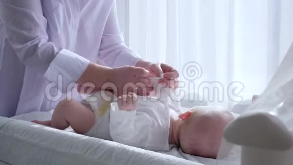 母亲的温柔母亲穿着孩子和亲吻腿在明亮的房间靠在窗帘上视频的预览图