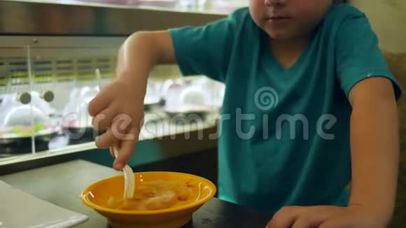 食堂里的小男孩吃烤鸡里面有塑料叉子坐在桌子上视频的预览图