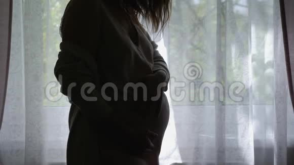 穿着裙子站在窗前侧影的孕妇视频的预览图