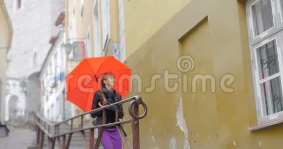 老城区鹅卵石街道上带着红伞的女人视频的预览图