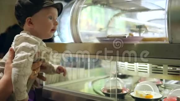 在咖啡馆里一个惊讶的孩子在橱窗里看着不同的寿司在移动的盘子里视频的预览图