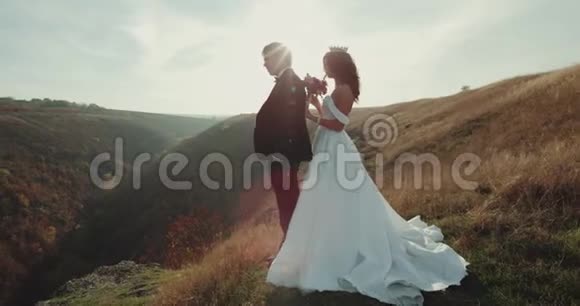 在山顶上美丽的夕阳新娘抱着她的新郎4k视频的预览图