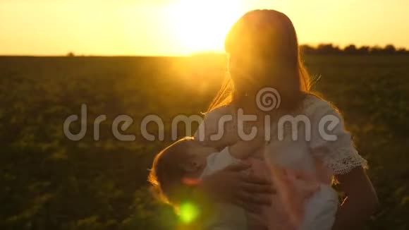 小女孩正睡在年轻妈妈的怀里在金色的夕阳下慢动作视频的预览图