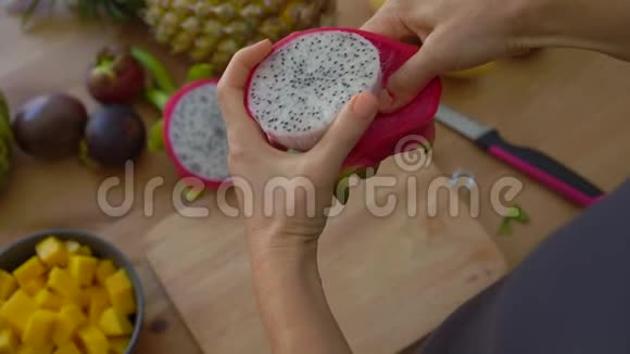 4倍慢镜头拍摄一位年轻女子剥着火龙果桌上摆着许多热带水果视频的预览图