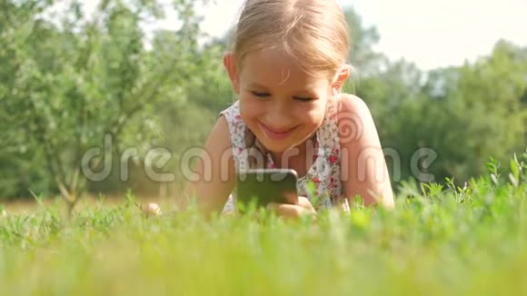 孩子用手机躺在绿草中视频的预览图