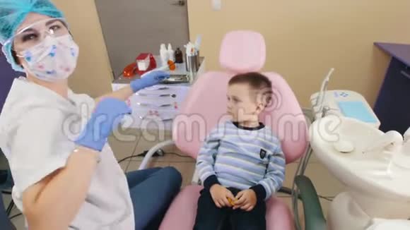 一个戴牙科的男婴坐在病人的椅子上张开嘴视频的预览图