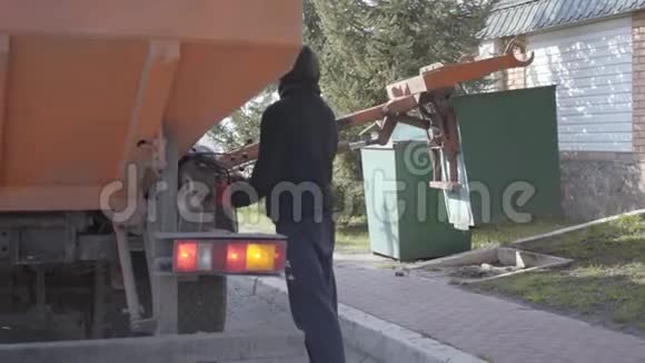 后视图男子控制垃圾机工作穿便服的工人用垃圾机把垃圾桶装起来视频的预览图