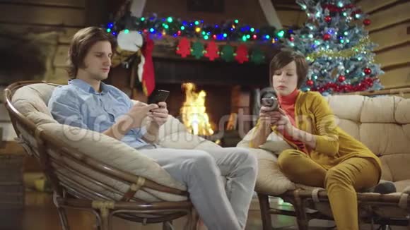 男人和女人一起在圣诞夜使用智能手机视频的预览图