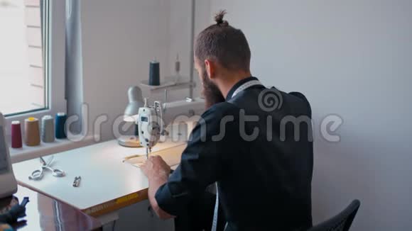 裁缝在自己的工作室里开始缝制时尚男士衣服视频的预览图