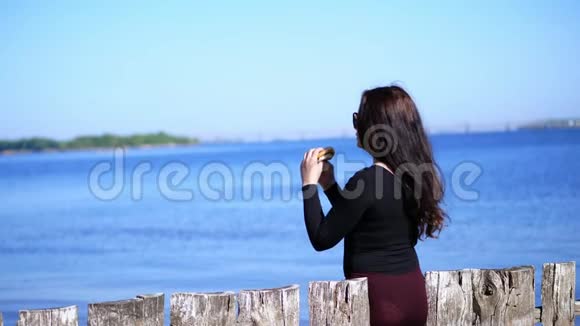 夏天靠近海边女人留着长长的黑发戴着太阳镜爱吃快餐吃汉堡包视频的预览图