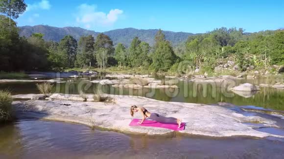 女孩在画河的平地上做瑜伽视频的预览图