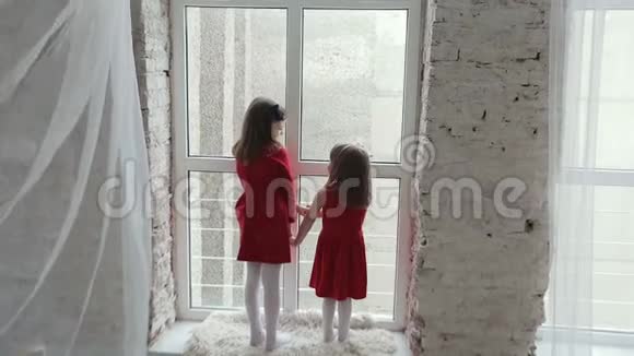 两个穿红色衣服的女孩靠近大窗户视频的预览图
