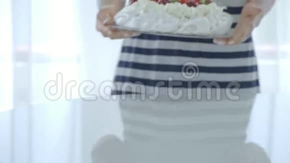 女性在桌子上放着带有浆果的白色蛋糕巴甫洛夫甜点视频的预览图