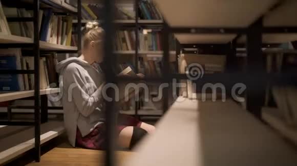 坐在书架间看书的年轻女学生视频的预览图