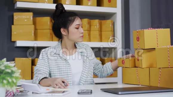 年轻女性企业家在自己的工作中在网上购物时检查包裹箱视频的预览图