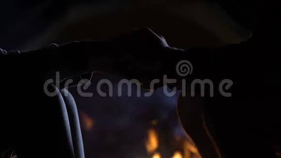 可爱的男人牵着女朋友的手可爱的夫妇坐在篝火旁视频的预览图