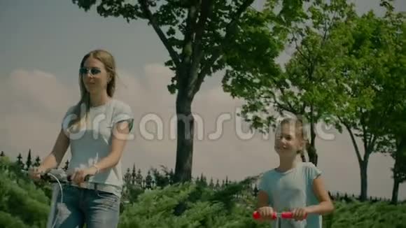 妈妈带着可爱的女儿骑着滑板车视频的预览图