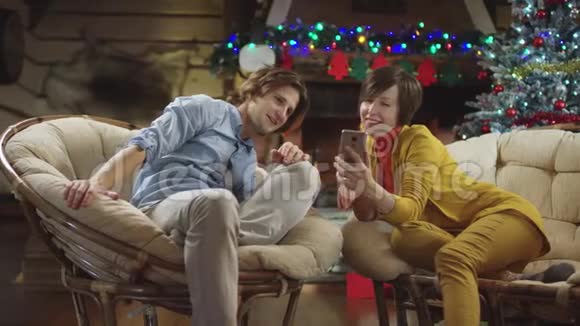 男人和女人在圣诞夜看智能手机视频视频的预览图