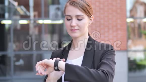年轻女商人使用智能手表户外视频的预览图