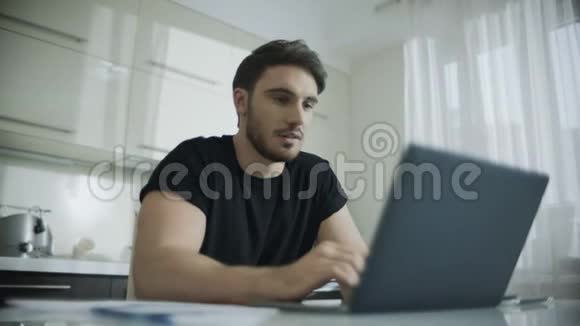 快乐的男人在家里的笔记本电脑上在线聊天微笑男人聊天视频的预览图