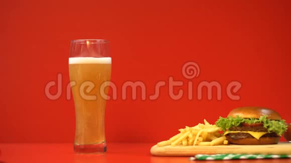 红色背景下的啤酒泡沫和汉堡包碳水化合物和脂肪食品视频的预览图