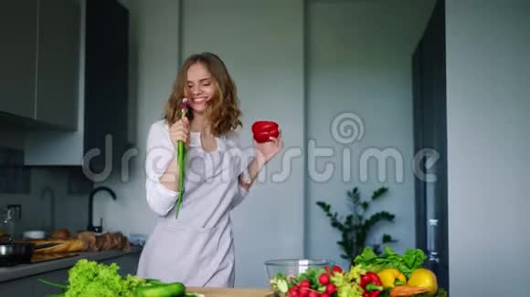 用黄瓜作为麦克风在厨房跳舞唱歌的快乐女孩视频的预览图