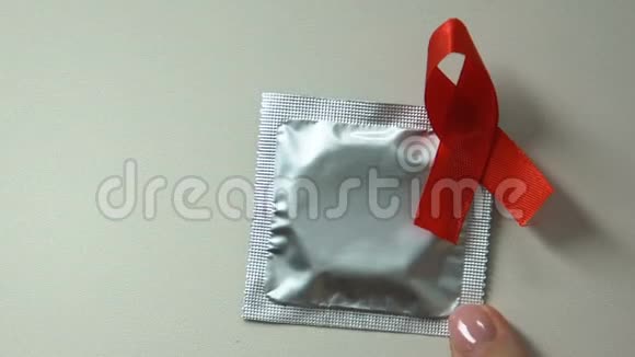 女人把带红丝带的避孕套安全的性提示预防艾滋病医疗保健视频的预览图