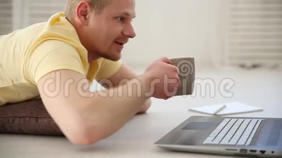 一个自由职业者的工作中断一个男人在地板上的笔记本电脑上与同事视频聊天喝酒视频的预览图